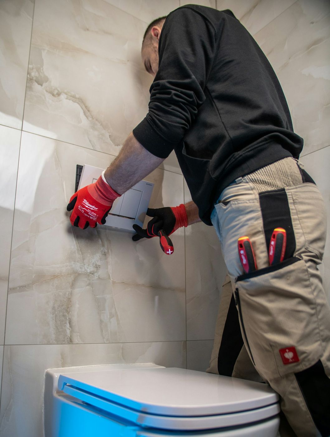 A plumber fitting a wall-hung toilet